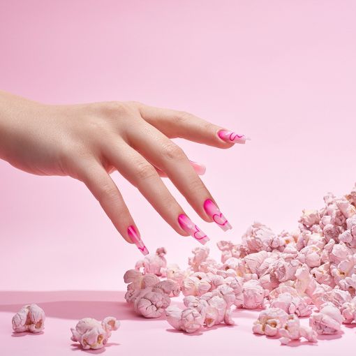cupio_pinx_feb_202503237_copy_1_11 Hand mit pinkem Nageldesign, die auf eine Menge rosa Popcorn zeigt