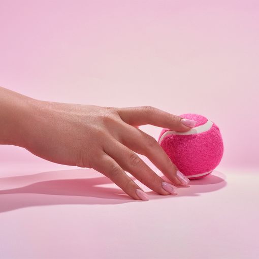 cupio_pinx_feb_202503183_copy_1_11 Merkmale einer Hand, die einen pinken Tennisball auf einem rosa Untergrund berührt